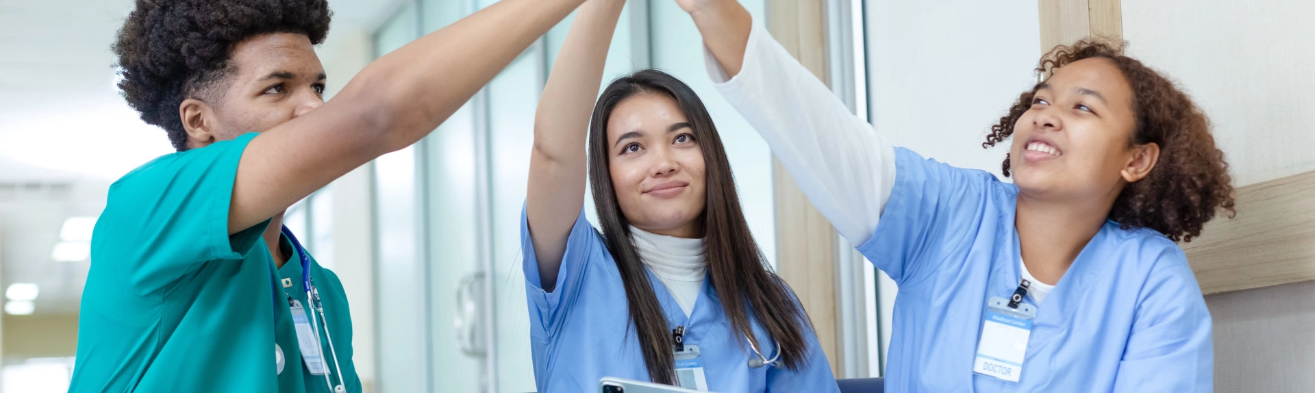 Three nursing students raising their hands together