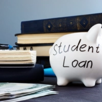 Books and a piggy bank with student loan written on it