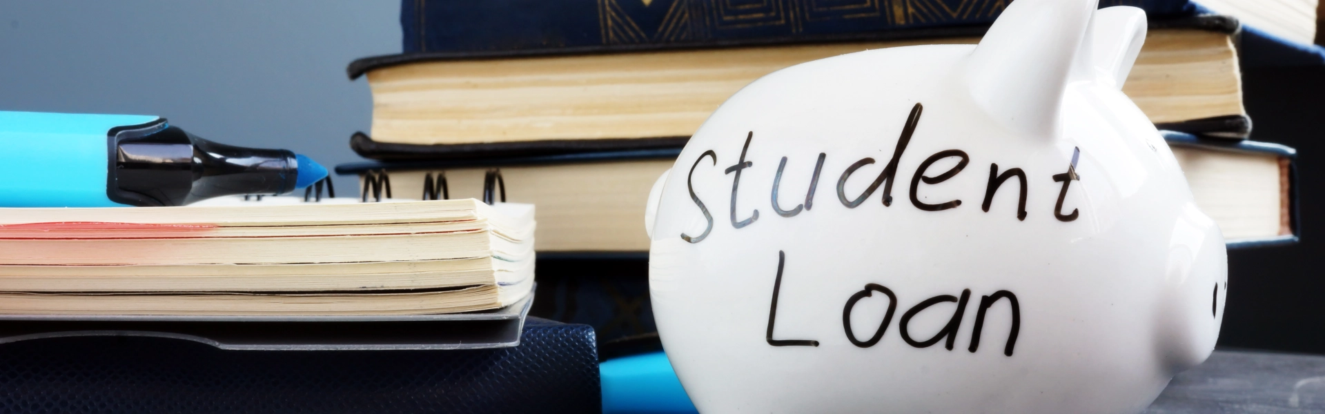 Books and a piggy bank with student loan written on it