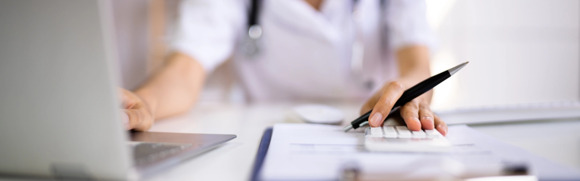 A female nurse looking at a laptop and a calculator on the table